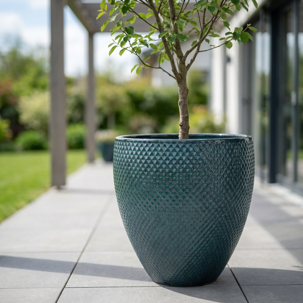 Petrolejově modrý keramický květináč Signac s buxusem v detailním záběru na moderní rodinné terase v jarním slunci.