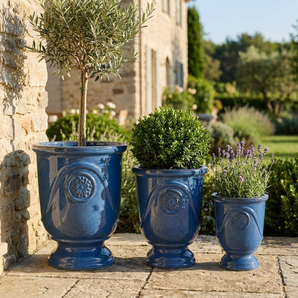 Detail ručně vyráběného glazovaného keramického květináče Moliere Anticky modrý z terakoty s ozdobným reliéfem a olivovníkem na slunné terase.