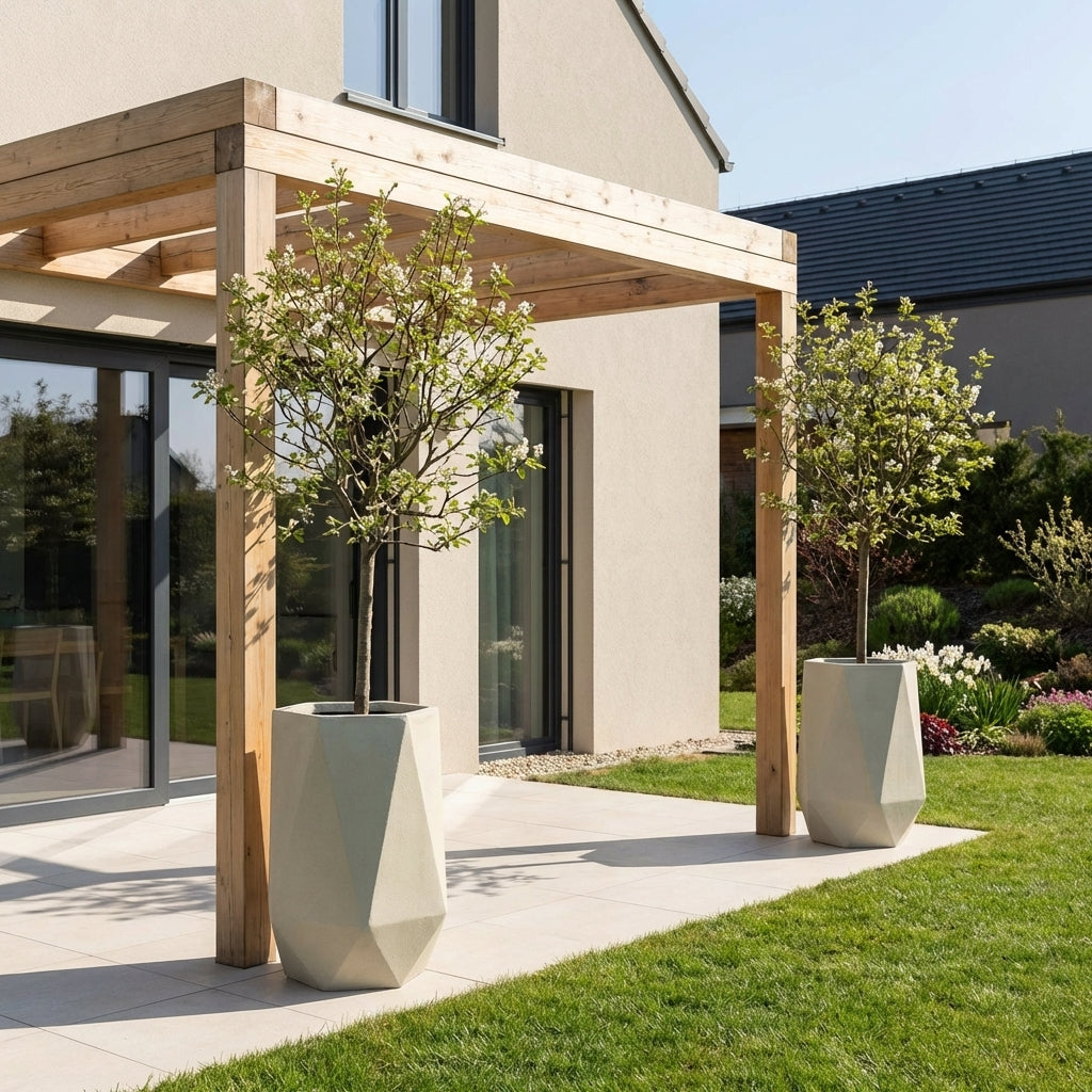 Detailní záběr na betonový květináč PRISME v béžové barvě se stálezeleným keřem na moderní prosluněné terase.