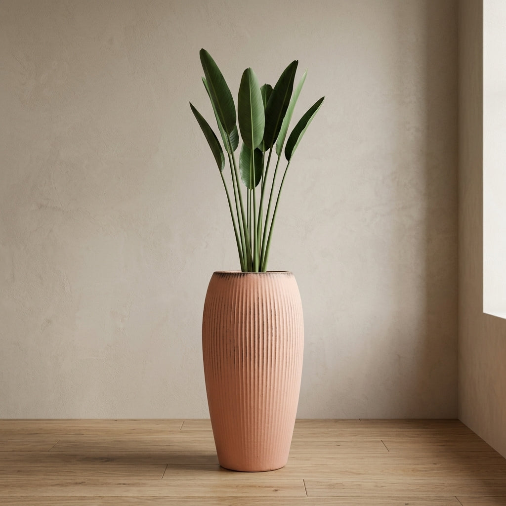 Keramický květináč Milano - Růžová o výšce 61 cm se vzrostlou strelitzií v moderním skandinávském interiéru. Detail ženy, která se jemně dotýká listů rostliny.