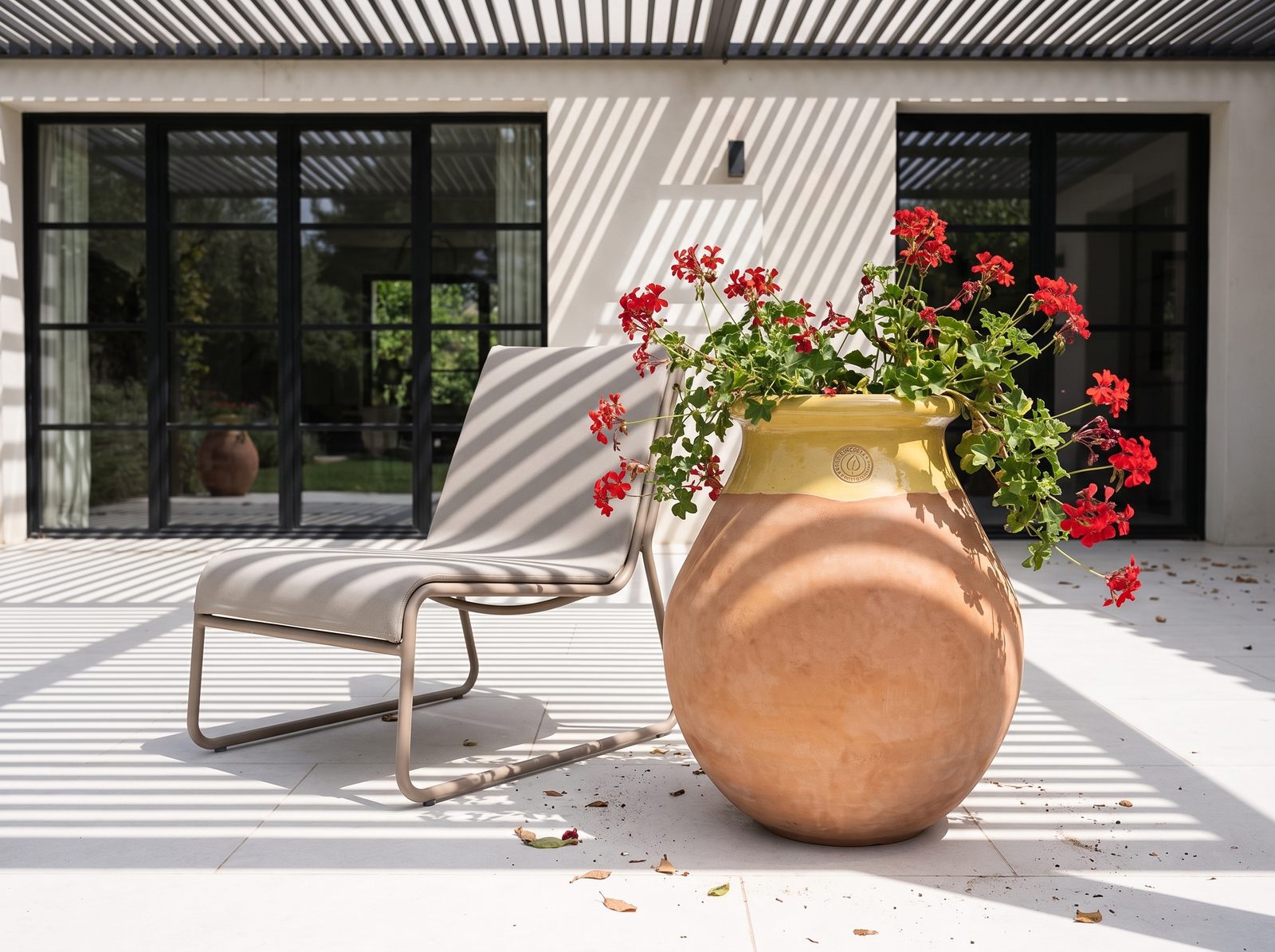 Biot mit roten Pelargonien auf der Terrasse einer modernen Villa